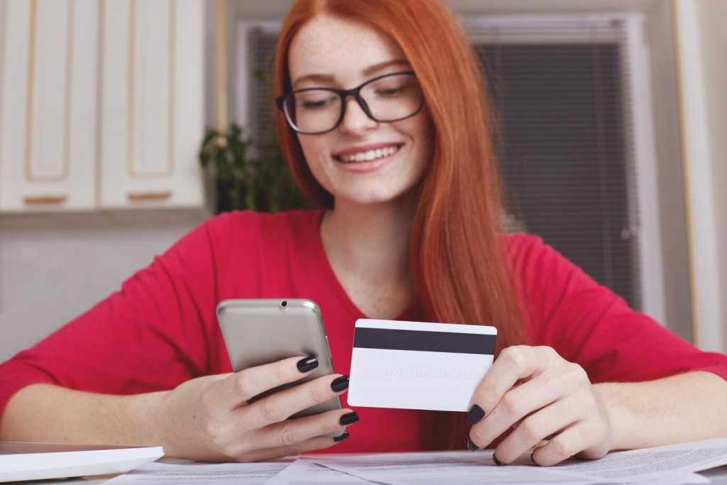 redhaired-pretty-female-model-eyewear-holds-smart-phone-credit-card_176532-7577.jpg телефон